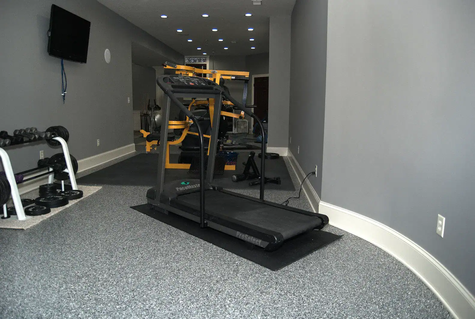 Home gym with concrete flooring coating and treadmill